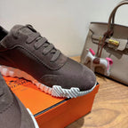 Grey suede lace-up sneakers close-up, white ribbed sole and stitched panel, Hermes