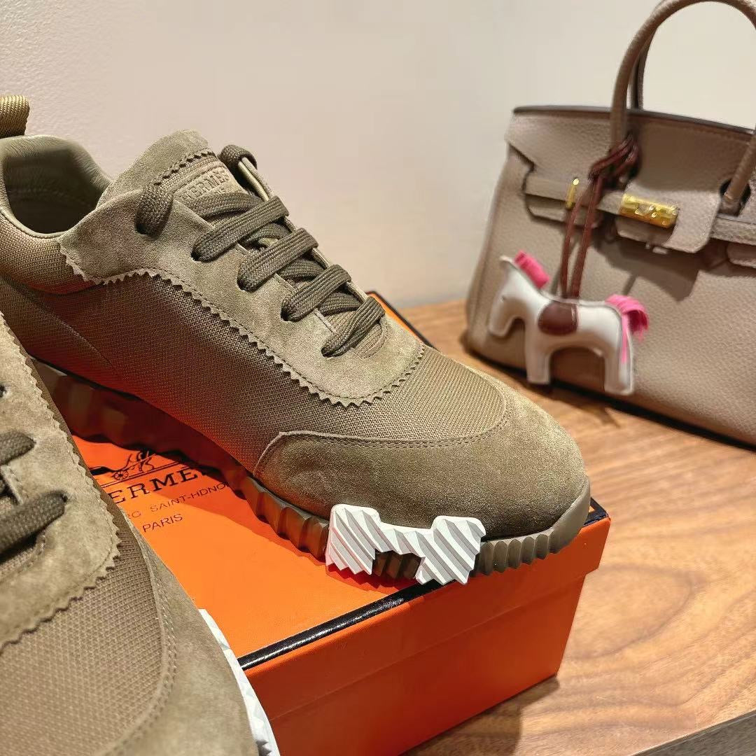 Hermes unisex suede sneaker close-up, olive lace-up with serrated white sole detail