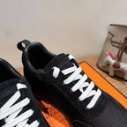 Hermes unisex sneakers, black close-up with white lace-up eyelets and stitched toe