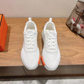 Hermes unisex white sneakers with lace-up front and orange-striped rubber soles