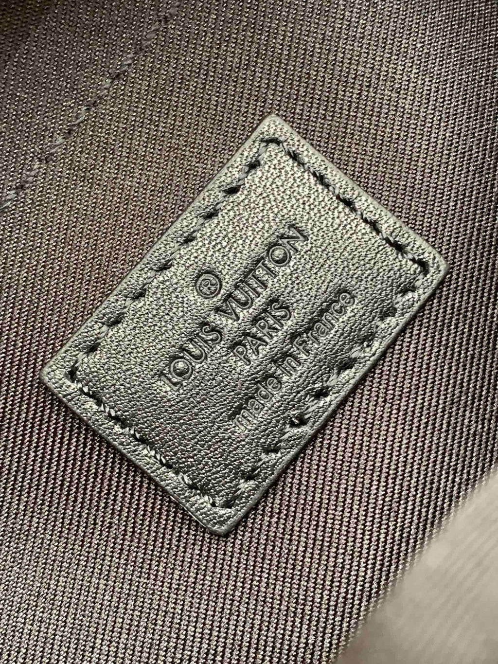 Men’s Louis Vuitton bag close-up of fabric logo label patch