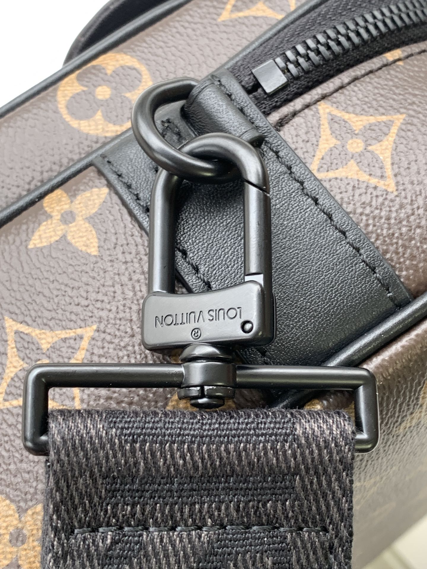 Men's Louis Vuitton monogram bag hardware closeup with engraved push-lock