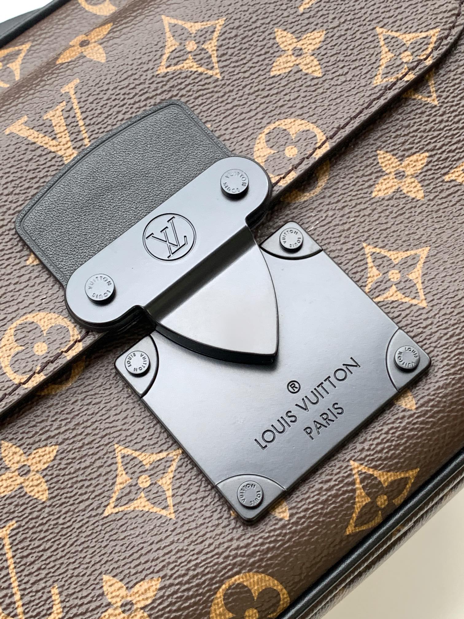 Men's Louis Vuitton monogram bag closeup with front clasp and Louis Vuitton tag