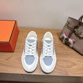 White and light-blue lace-up sneakers with low profile rubber sole.