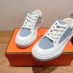 White and light-blue lace-up sneakers with white rubber sole and lace-up front.