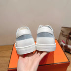 White and light-blue sneakers, close rear view showing cushioned collar and stitching.