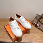 White leather lace-up sneakers with tan rubber sole, front view