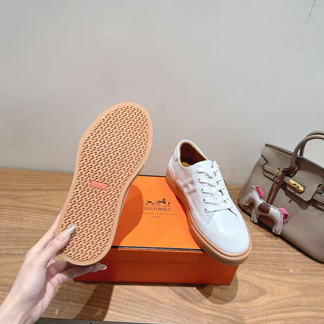White sneaker outsole with tan tread, shown above shoe box