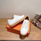 White leather lace-up sneakers with tan rubber sole, angled side view