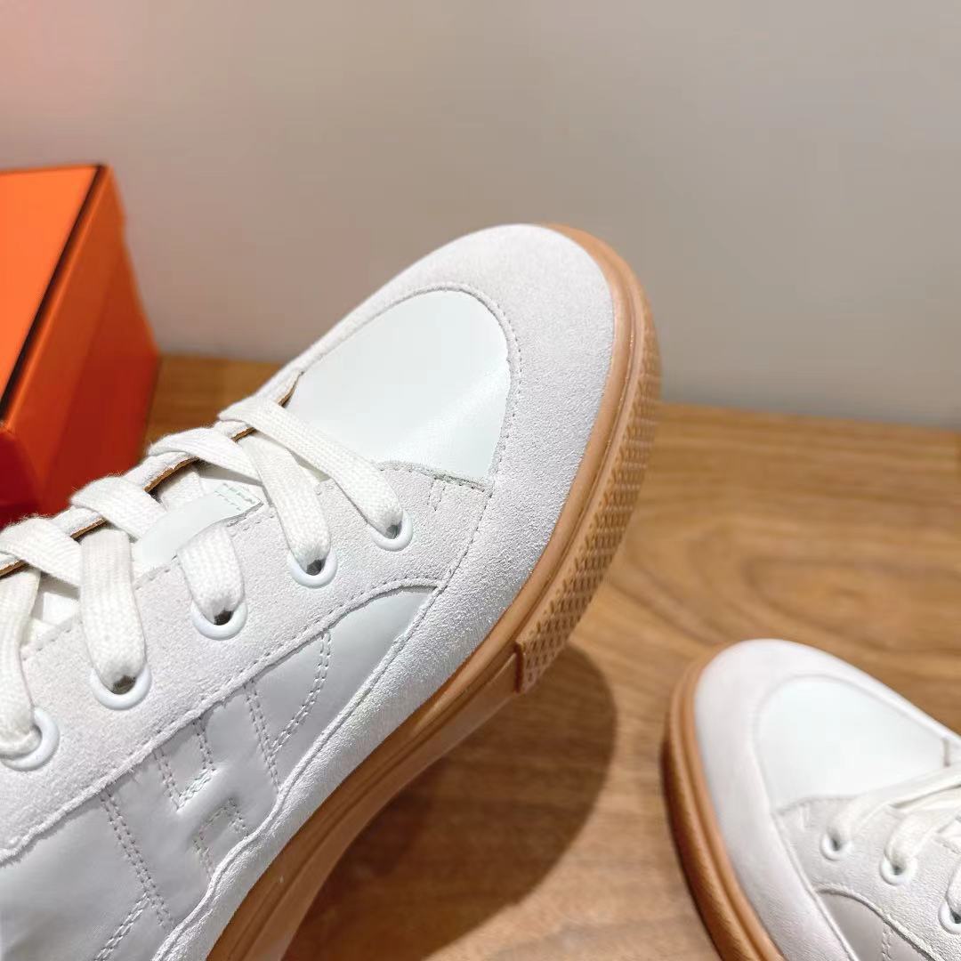 White leather sneaker close-up, lace eyelets and tan rubber sole