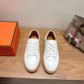 White leather lace-up sneakers with tan rubber sole, round toe