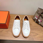 White leather lace-up sneakers with tan rubber sole, round toe