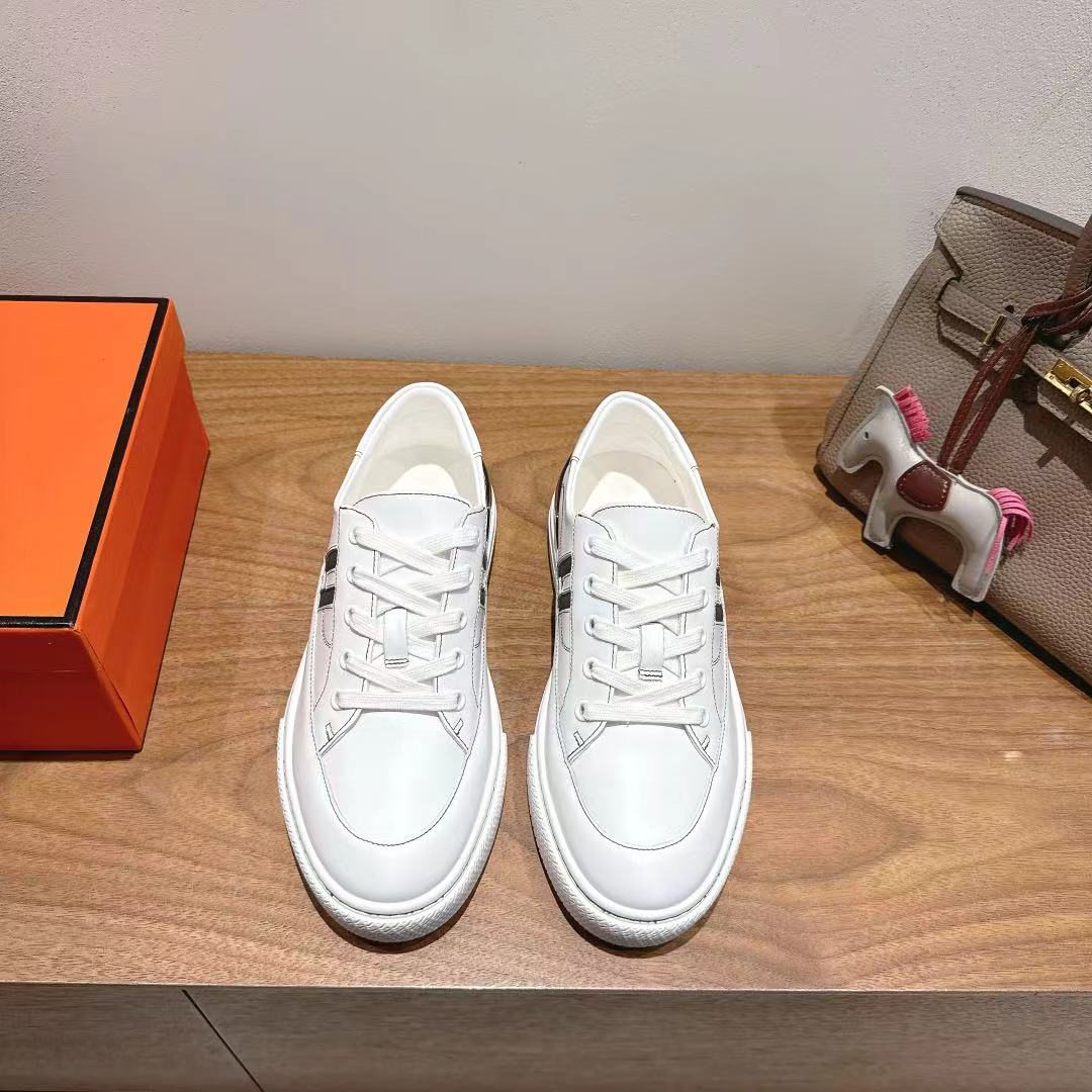 White Hermes unisex luxury shoes with white laces and black logo accents.