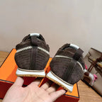 Heel view of dark gray lace-up sneakers with white midsoles and brown textured outsoles.