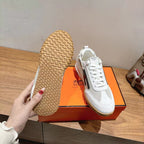 Hermes unisex white sneaker outsole view with textured tread and side stripe.