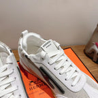 Hermes unisex white sneaker close-up with lace-up front and dark side stripe.