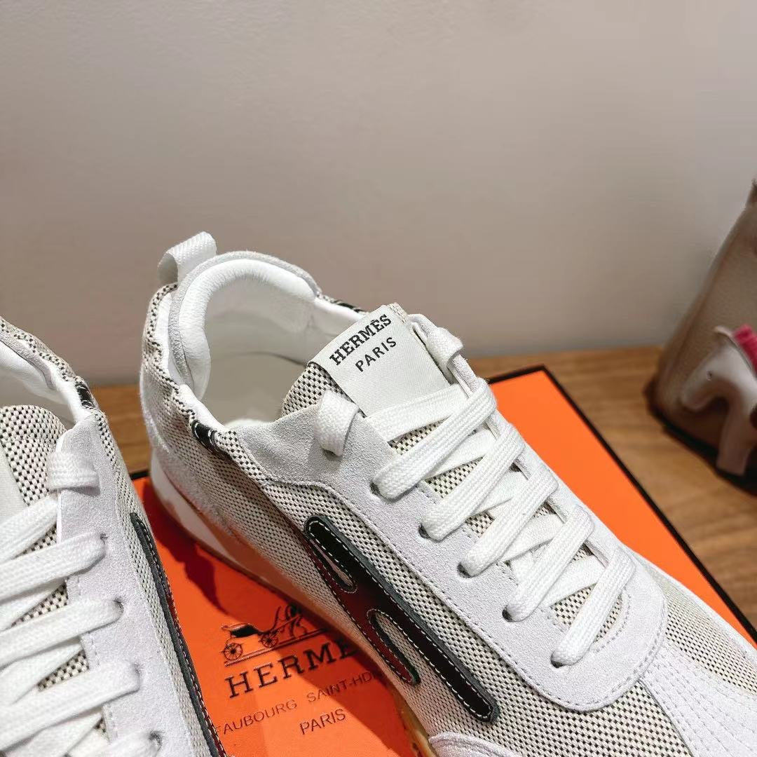 Hermes unisex white sneaker close-up with lace-up front and dark side stripe.
