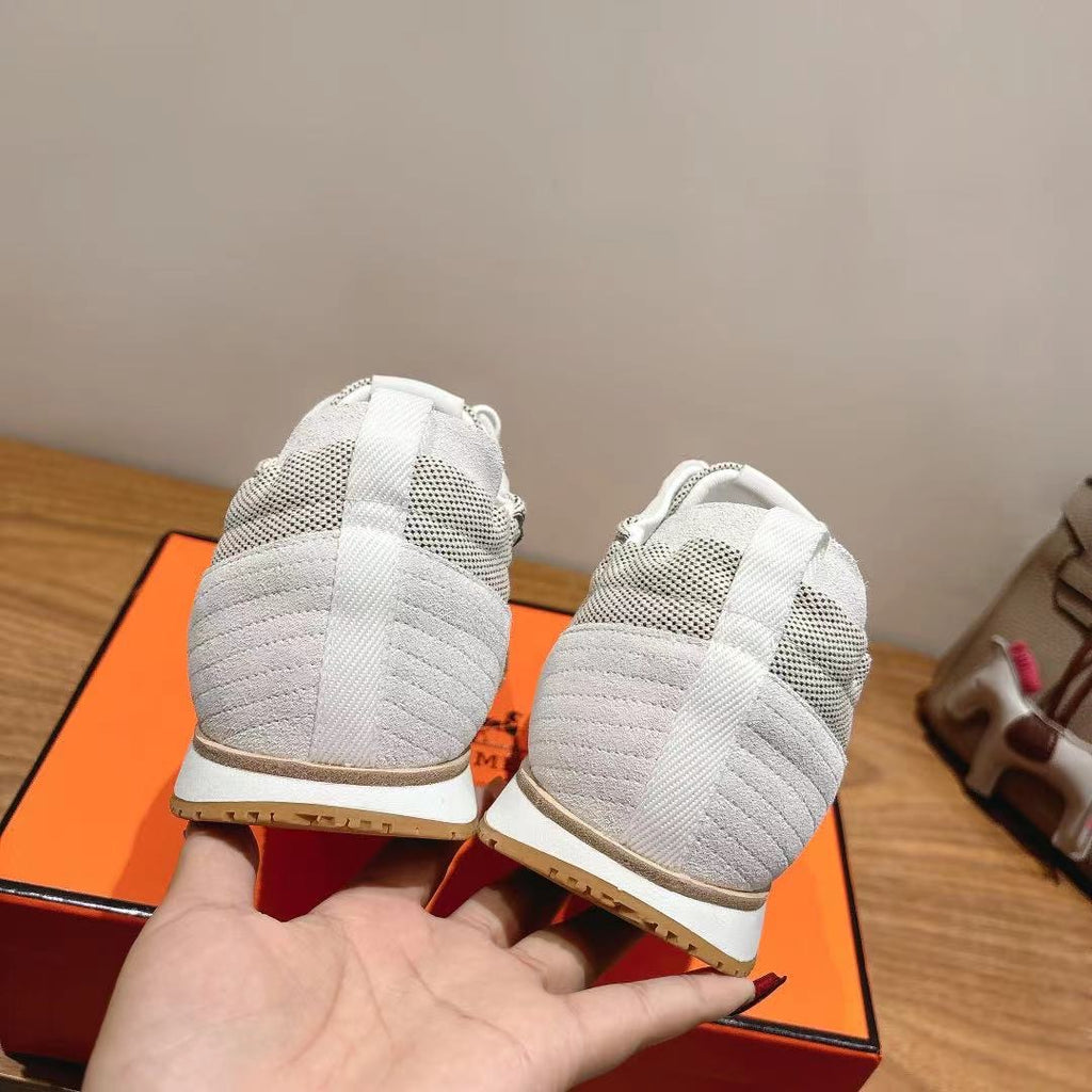 Hermes unisex white sneakers heel view, textured lining and gum sole edges.
