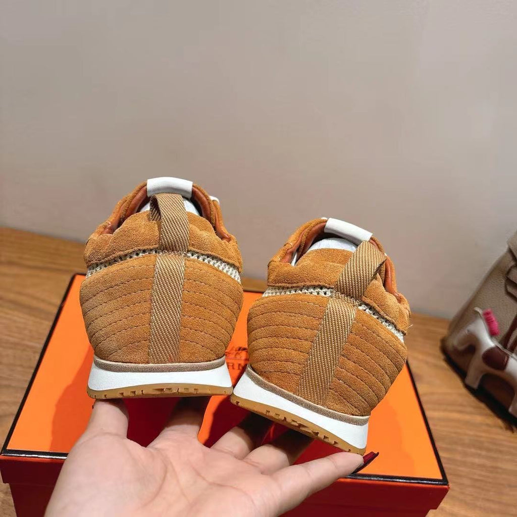 Hermes unisex sneakers from heel view, tan suede with white stripe and sole.