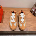 Hermes unisex sneakers with tan suede panels, white laces, and rubber sole.