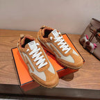 Hermes unisex sneakers in tan and white, shown with orange display box.