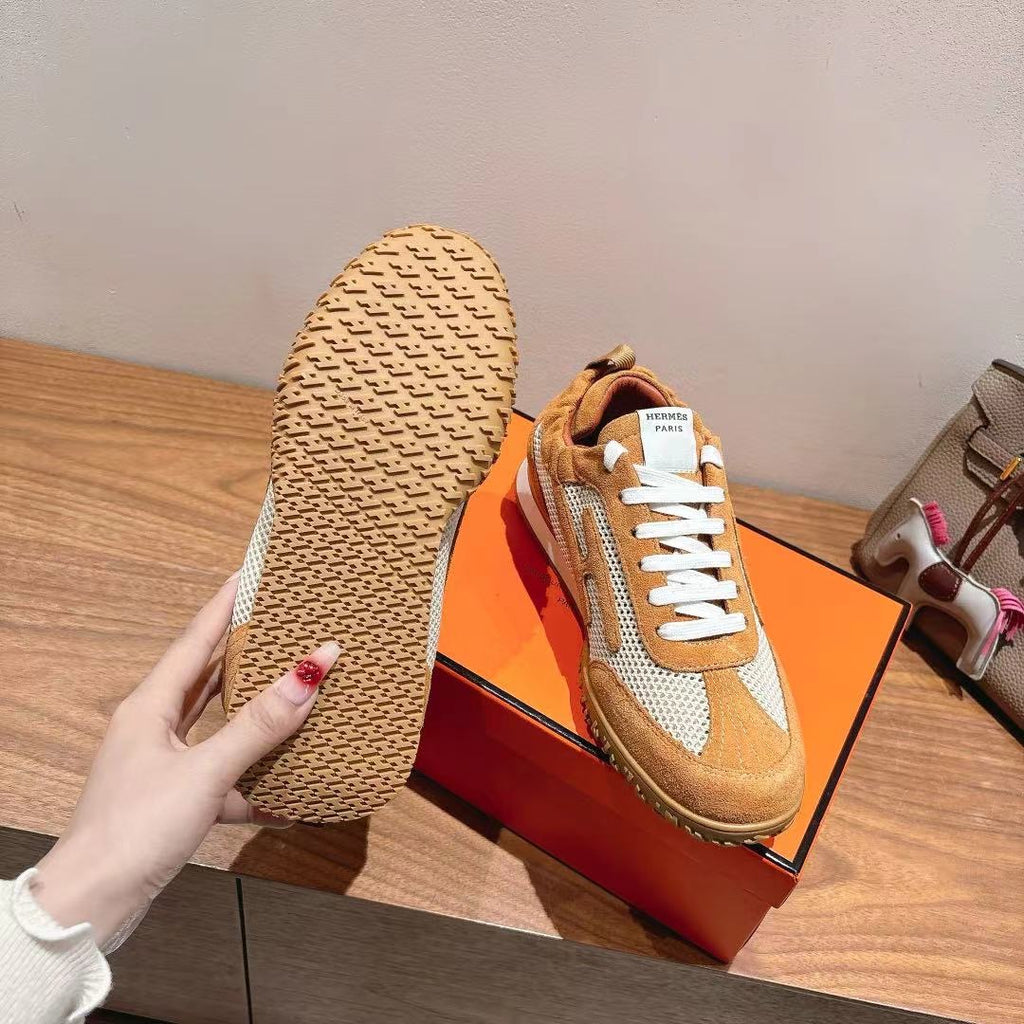 Hermes unisex sneaker with tan outsole and white laces, on orange box.