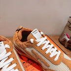 Hermes unisex sneaker close-up with white laces and tan suede over mesh panel.