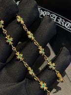 Gold bracelet with green star charms on black fabric display