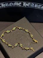 Gold bracelet with green star/flower charms and linked settings on display card