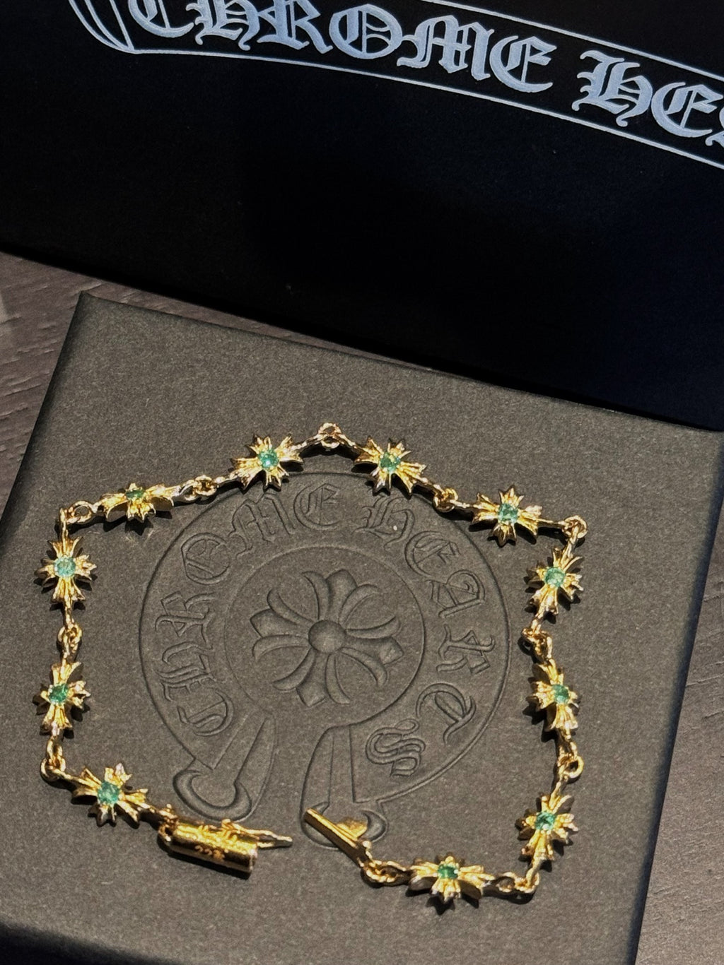 Gold chain bracelet with green star-shaped gemstones, ornate linked charm frame