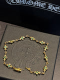 Gold chain bracelet with green star-shaped gemstones, ornate linked charm frame