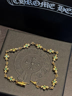 Gold chain bracelet with green star-shaped gemstones, ornate linked charm frame