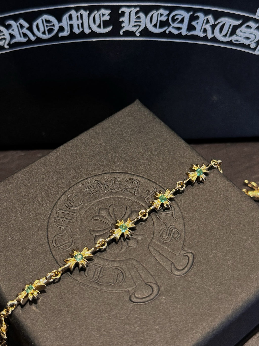 Gold bracelet detail with green star charms arranged in a straight line