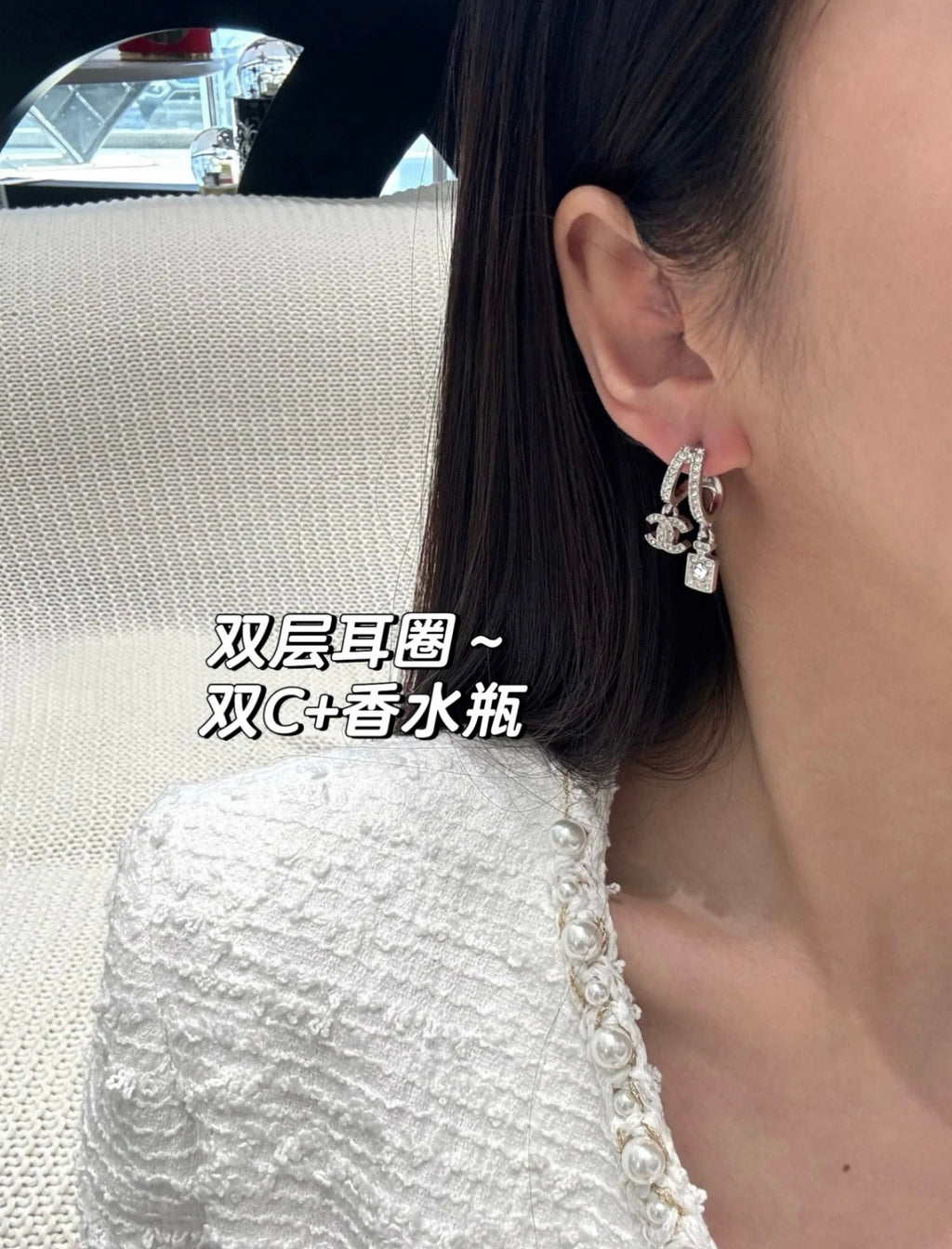 Hoop earrings with dangling charms, silver-tone, angled close-up on ear