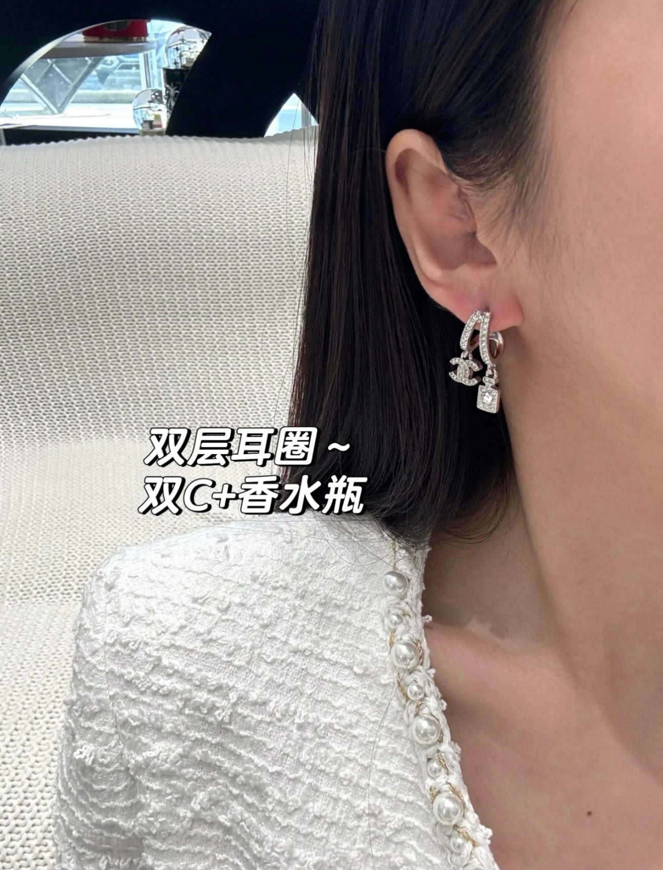 Hoop earrings with dangling charms, silver-tone, angled close-up on ear