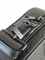 Louis Vuitton monogram bag detail: dark leather strap with metal buckle and engraved plaque