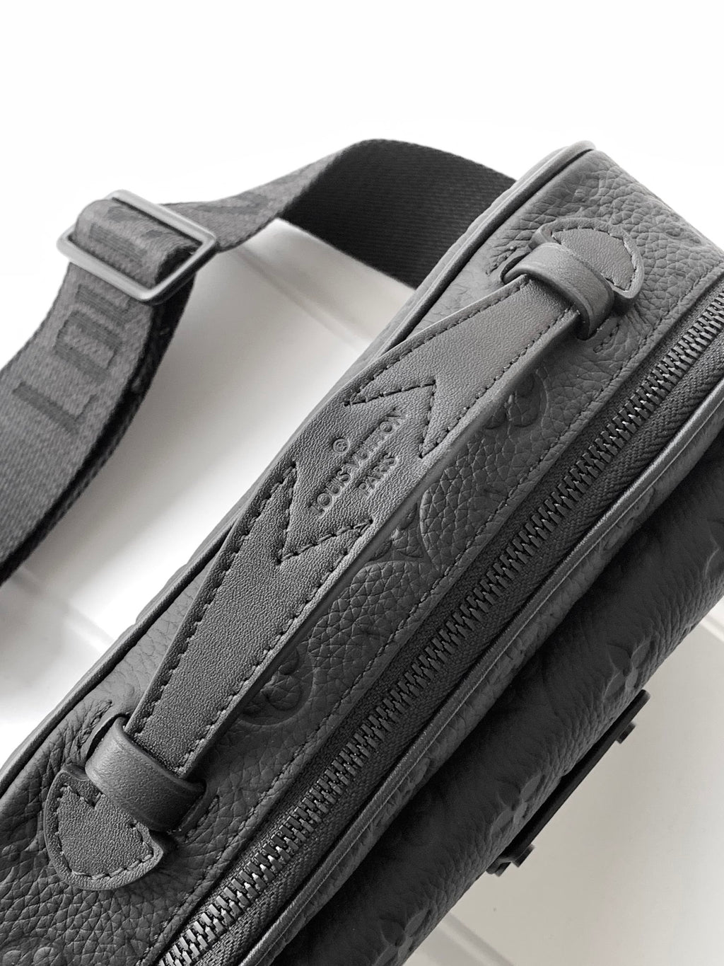 Louis Vuitton monogram crossbody bag, dark leather, close-up of zip pull and embossed logo