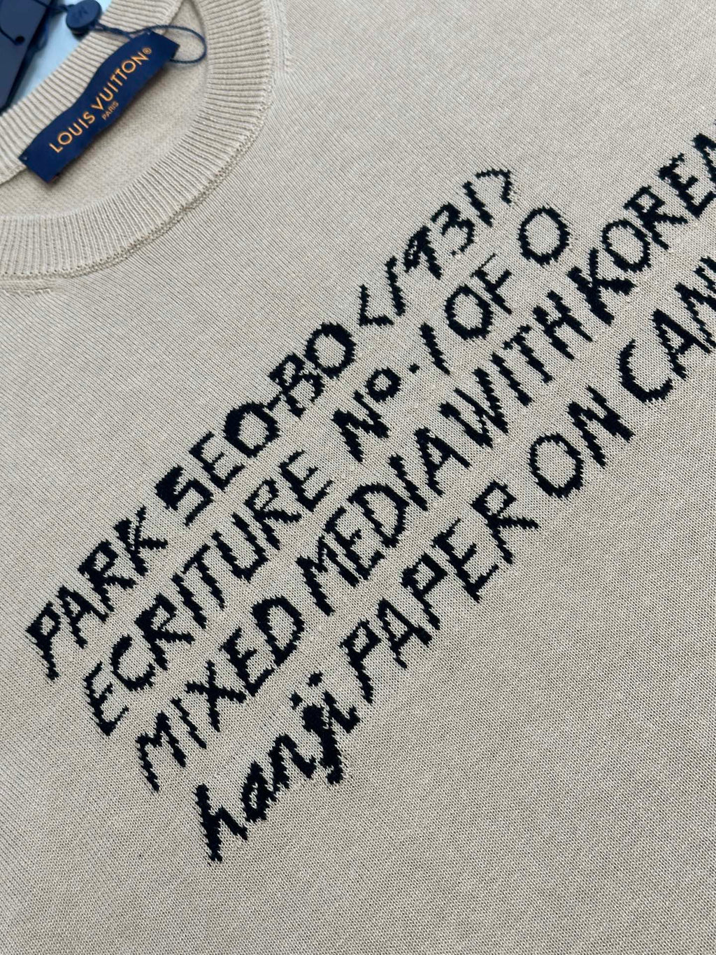 Light beige T-shirt with black text graphic print, close-up on front lettering