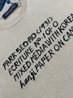 Light beige T-shirt with black text graphic print, close-up on front lettering