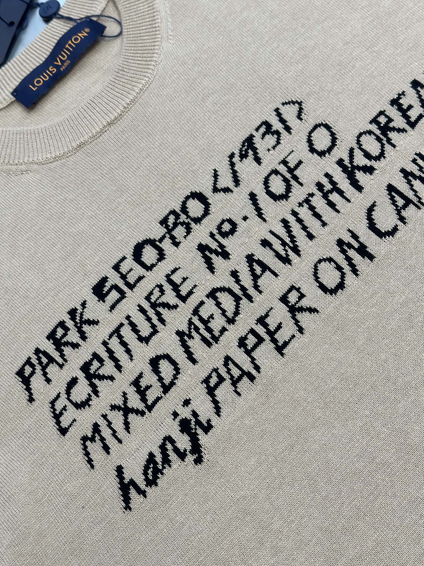 Light beige T-shirt with black text graphic print, close-up on front lettering