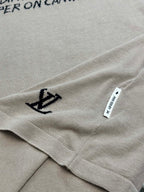 Light beige T-shirt hem detail with small black anchor icon and white care label