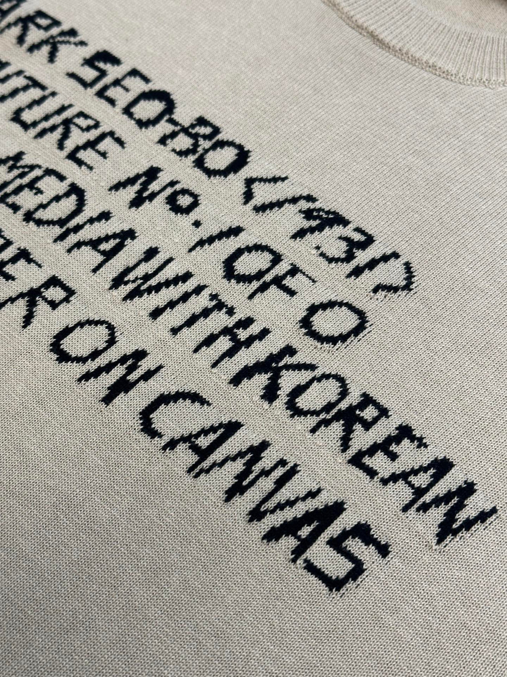 Close-up of light beige T-shirt with black text graphic lettering print