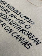 Close-up of light beige T-shirt with black text graphic lettering print