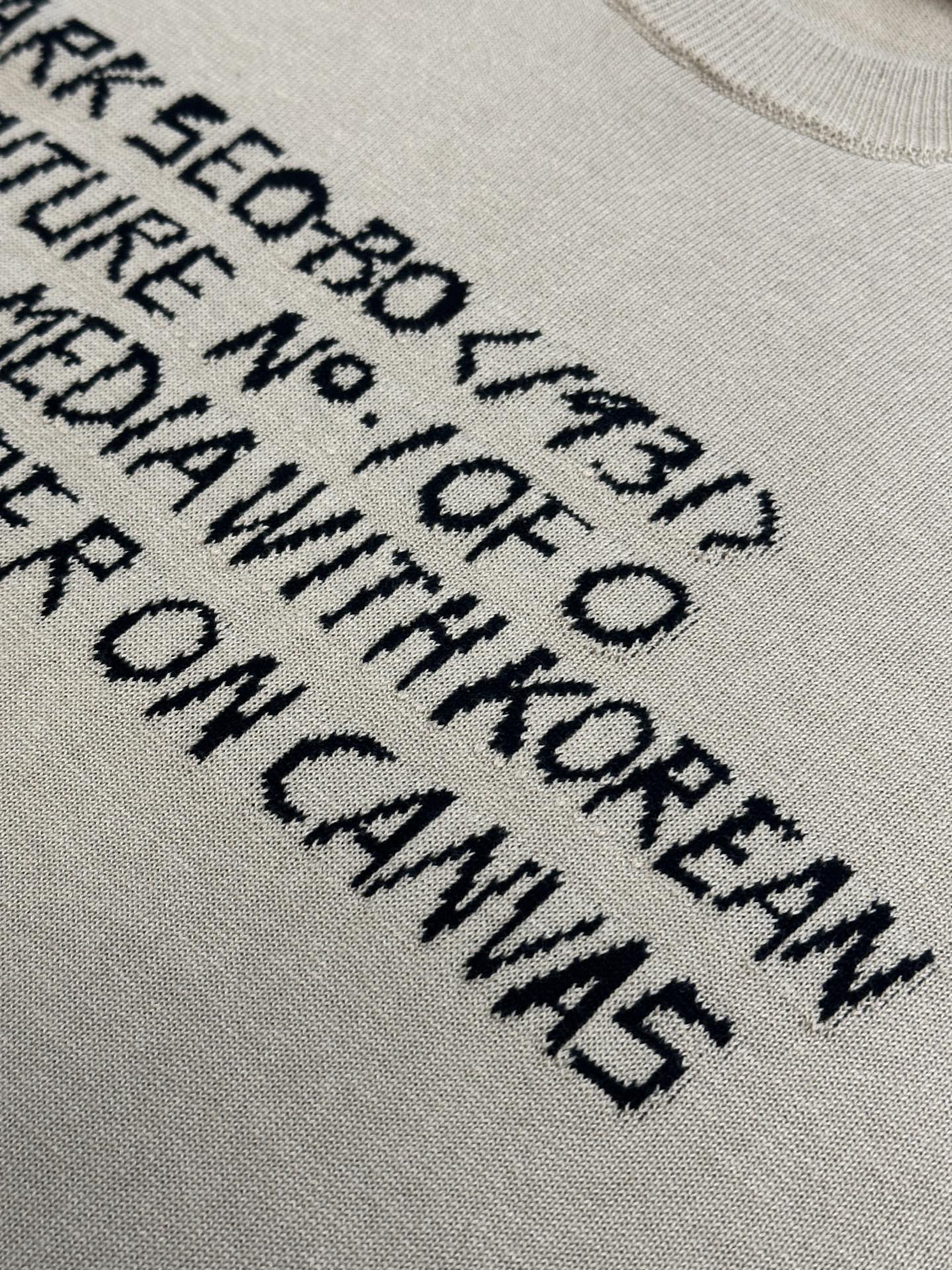 Close-up of light beige T-shirt with black text graphic lettering print