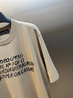 Light beige T-shirt sleeve with black graphic text print, knit cuff on hanger
