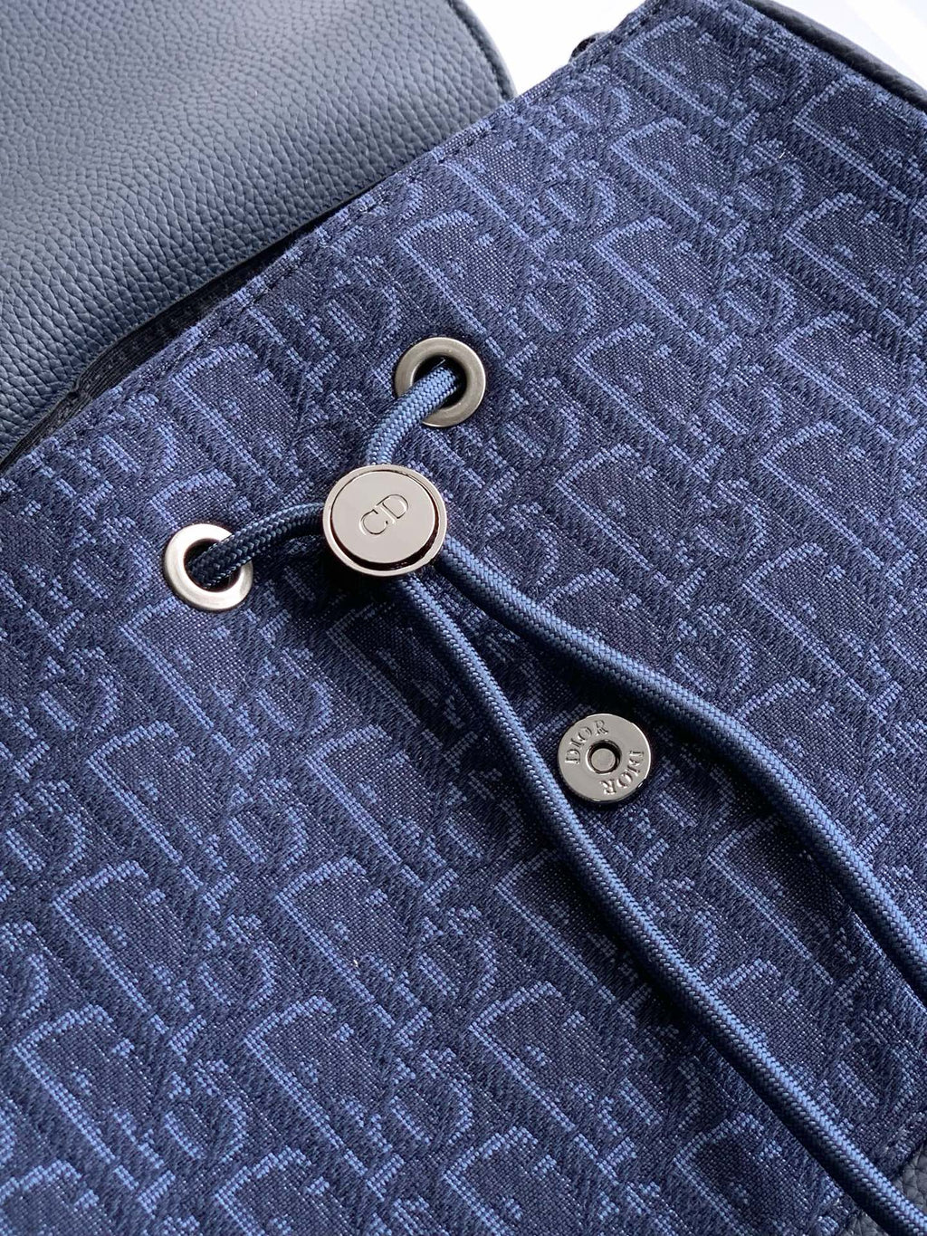 Dior bag close-up of blue monogram fabric with zipper pull and metal eyelets