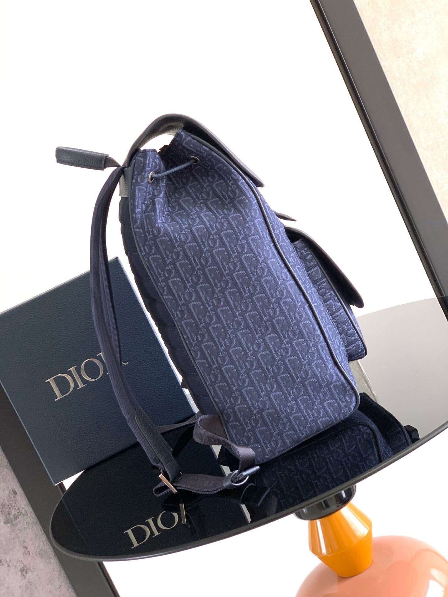 Dior bag angled view with blue monogram exterior, gray trim, adjustable shoulder strap