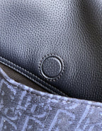 Dior bag front close-up, navy grained leather with oval snap accent
