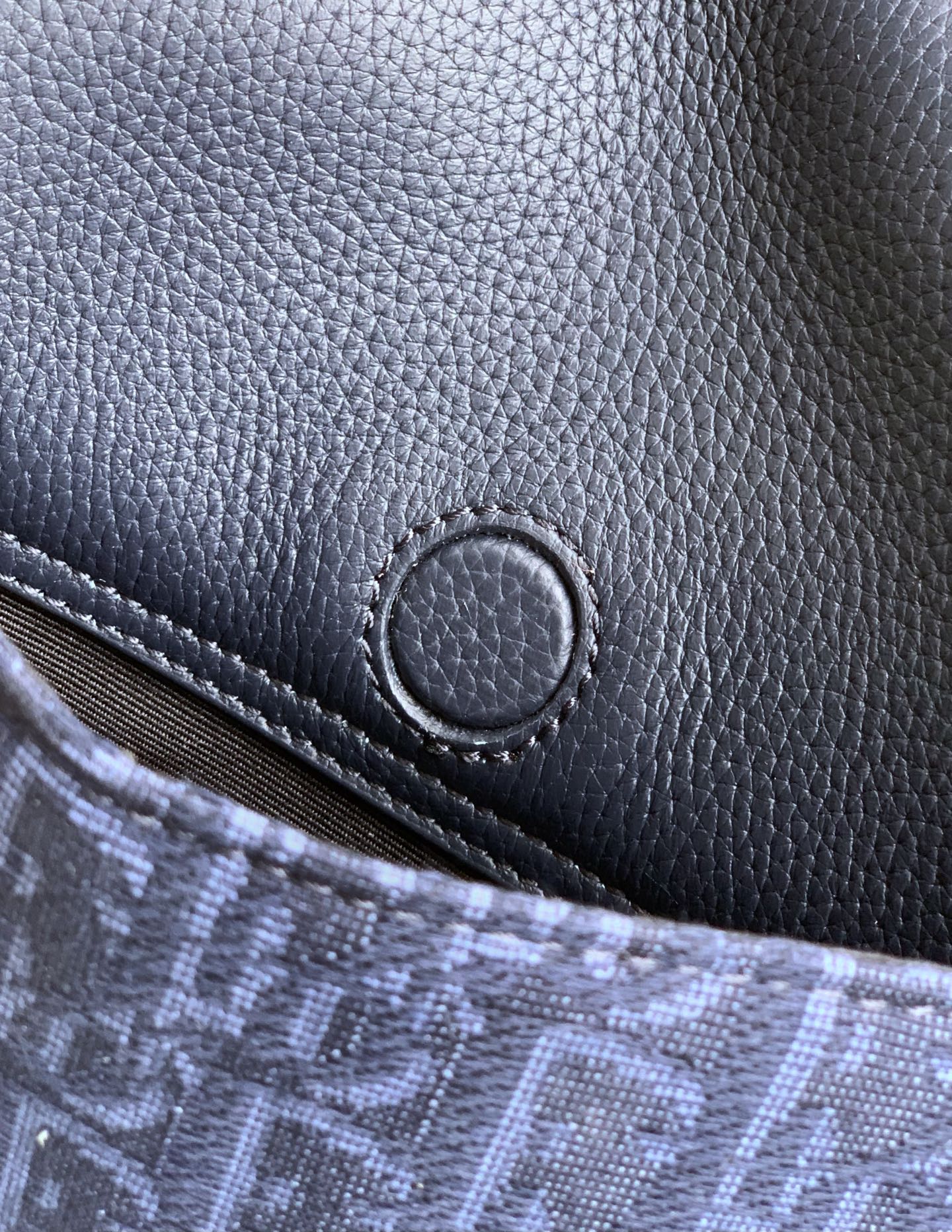 Dior bag front close-up, navy grained leather with oval snap accent