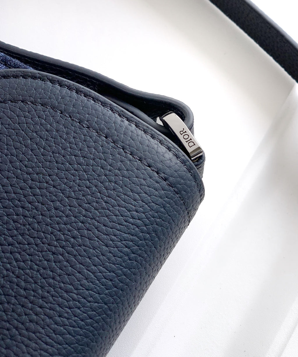 Navy Dior bag close-up of pebbled leather side and curved flap edge.